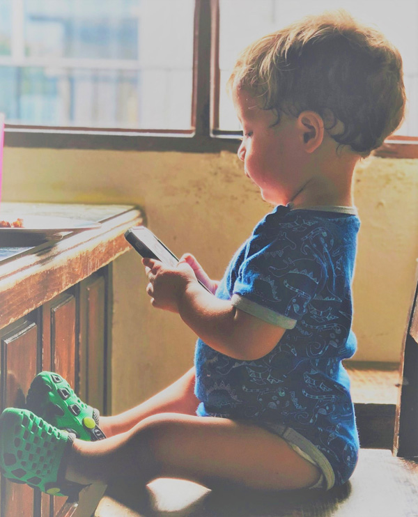 Une enfant sur une chaise, jouant avec un téléphone